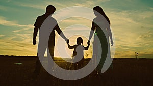 silhouette affectionate parents with child sunset. happy african family sunset park. mother father hold kid hands