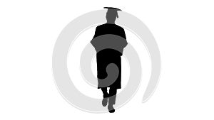 Silhouette African american male student in graduation robe texting on the phone while walking with his diploma.