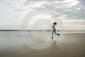 Silhouette of African American woman running on the beach - young attractive and athletic black girl training outdoors doing