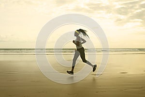 Silhouette of African American woman running on the beach - young attractive and athletic black girl training outdoors doing