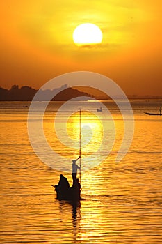 Silhouette of African fisherman in canoe at sunset