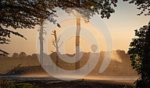 Silhouette of agricultural irrigation system watering cornfield at sunset. Cornfield irrigation using the center pivot sprinkler