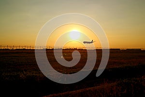 Silhouette of an airplane flying up against sunset sky