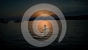 Silhouette of alone paddleboarder sailing into the evening sunset in Majorca, Spain