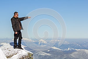 Silhouette of alone tourist standing on snowy mountain top enjoying view and achievement on bright sunny winter day. Adventure,