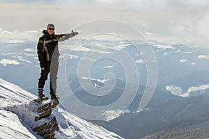 Silhouette of alone tourist standing on snowy mountain top in winner pose with raised hands enjoying view and achievement on