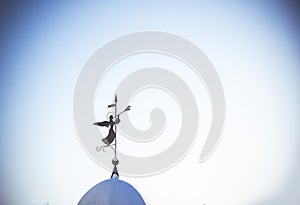 Silhouette of an angel. Weathervane on the dome of the temple against clean blue sky. The concept of peace and religion
