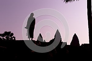 Silhouette of Angkor Wat and girl traveler with photo camera on the sunrise. Angkor Wat - Hindu temple complex in