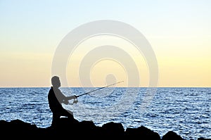 Silhouette of angler fishing on the rock at the beach of malacca straits