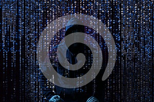 Silhouette of anonymous hacker and digital binary code on dark background. Cyber attack concept