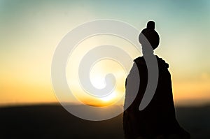 Silhouette of Arab man stands alone in the desert and watching the sunset with clouds of fog. Eastern Fairytale