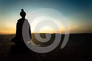 Silhouette of Arab man stands alone in the desert and watching the sunset with clouds of fog. Eastern Fairytale