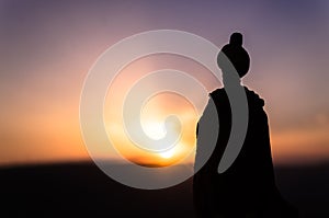 Silhouette of Arab man stands alone in the desert and watching the sunset with clouds of fog. Eastern Fairytale