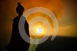 Silhouette of Arab man stands alone in the desert and watching the sunset with clouds of fog. Eastern Fairytale