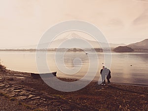 silhouette asia couple traveler 30s to 40s stand and take picture with boat on ground at side of lake kawaguchi on morning time w