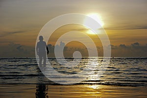 Silhouette of the asian boy standing at the beach during beautiful sunset