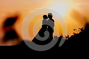 Silhouette of Asian Bride and Groom Standing on Mountain at Sunset