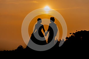 Silhouette of Asian Bride and Groom Standing on Mountain at Sunset