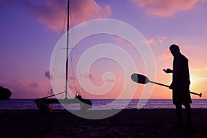 Silhouette asian man with paddle and sailing catamaran on the beach