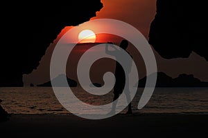 Silhouette of asian man stand and take sunset photo on beach in evening, Koh Samui