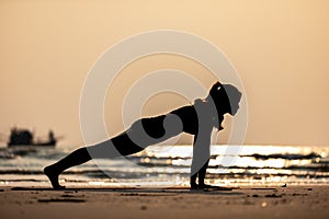 Silhouette of Asian woman practice yoga Plank or Phalakasana Pose on the sand and beach with sunset beautiful sea in Tropical isla