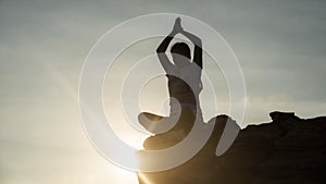 Silhouette Asian woman sit and perform lotus hands yoga meditation pose on mountain cliff peak