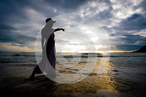 Silhouette of asian woman wearing stylish hat and clothes pointing at the sky and looking to the ocean