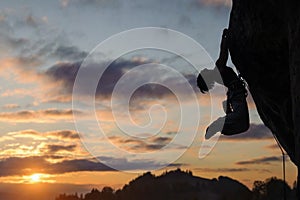 Silhouette of athletic woman climbing steep rock wall