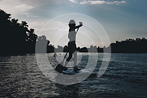 silhouette of athletic woman standup paddleboarding