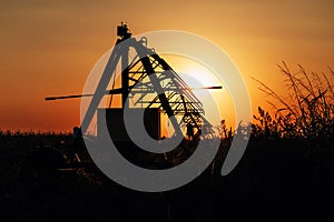 Silhouette of automated farming irrigation pivot sprinkler system in cultivated field in summer sunset