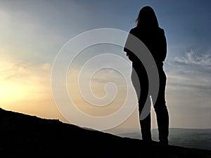 Silhouette of the back of a woman on the moors at sunset