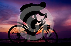 Silhouette of backpacker ride mountain bike beside sea