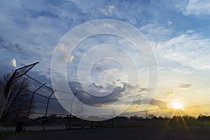 Silhouette of baseball diamond fence at dawn, beautiful sunrise