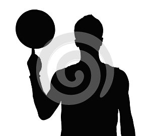 Silhouette of basketball player spinning basketball on finger.