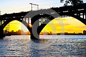 Silhouette of a beautiful arched railway bridge and wagons on the Dnieper river at sunset. Dnipropetrovsk