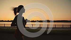 Silhouette of a beautiful asian girl run along the river. Solo activity or running alone. Taste of freedom. Playing