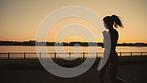 Silhouette of a beautiful asian girl run along the river. Taste of freedom. Playing sports at sunrise or sunset. Solo