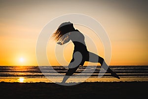 Silhouette of a happy dancer girl jumping the sunset