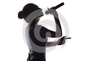 Silhouette of beautiful girl with hand-picked hair singing into microphone, profile of young woman face performing lyric song on