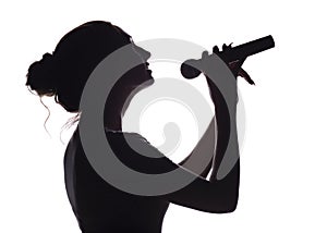 Silhouette of beautiful girl singing into microphone, profile of young woman face performing lyric song on white isolated