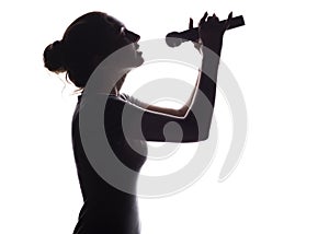 Silhouette of beautiful girl singing into microphone, profile of young woman face performing lyric song on white isolated