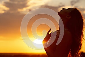 Silhouette of a beautiful girl at sunset in a field, face profile of young woman