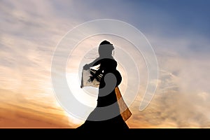 Silhouette of Beautiful Pregnant Woman Outside at Sunset Praising God