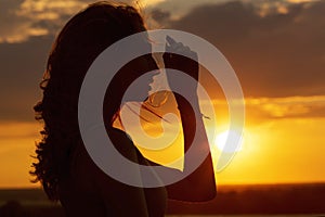 Silhouette of a beautiful romantic girl at sunset , face profile of young woman with long hair in hot weather