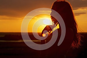 Silhouette of a beautiful romantic girl at sunset , face profile of young woman with long hair in hot weather