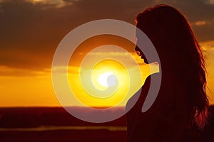 Silhouette of a beautiful romantic girl at sunset , face profile of young woman with long hair in hot weather