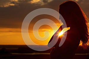 Silhouette of a beautiful romantic girl at sunset , face profile of young woman with long hair in hot weather