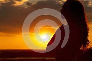 Silhouette of a beautiful romantic girl at sunset , face profile of young woman with long hair in hot weather