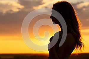 Silhouette of a beautiful romantic girl at sunset , face profile of young woman with long hair in hot weather