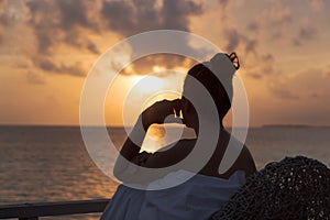 Silhouette of a beautiful woman contemplating sunrise from a balcony over the sea